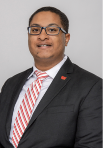 A man wearing glasses, smiling. 